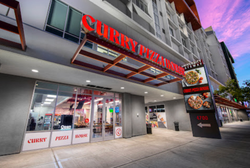 Exterior of Curry Pizza House with a modern design, featuring large signage and a welcoming entrance.
