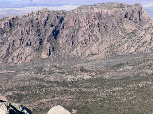 A panoramic view of rugged mountains with a small settlement nestled in the valley below.