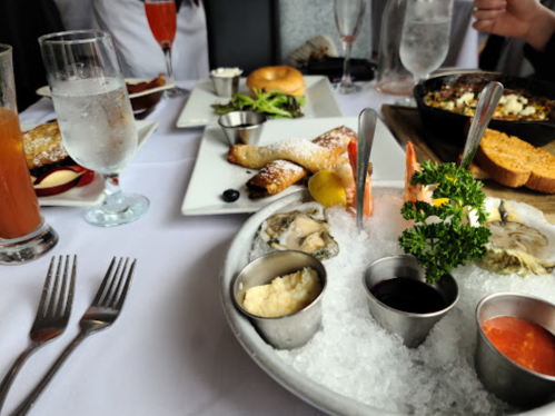 A table set with various dishes, including oysters on ice, drinks, and a plate of fried items.