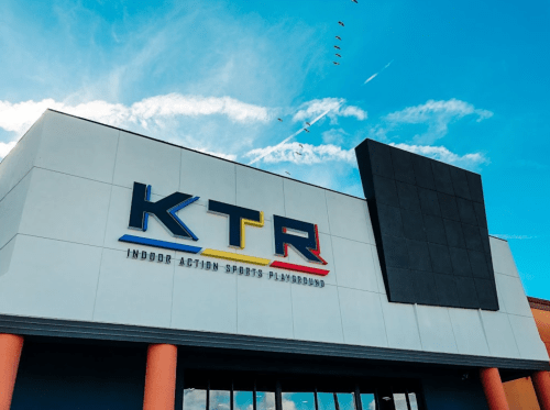Exterior of KTR Indoor Action Sports Playground, featuring a colorful sign against a blue sky.
