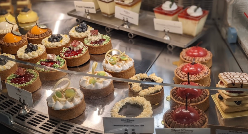 A display of assorted desserts, including tarts and cakes, beautifully arranged in a pastry shop.