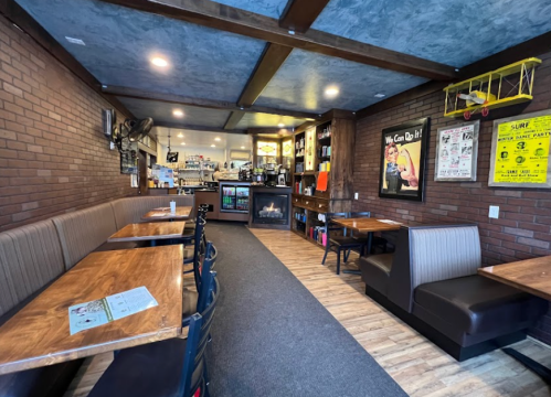 Cozy café interior with wooden tables, brick walls, and a counter in the background. Warm lighting creates a welcoming atmosphere.
