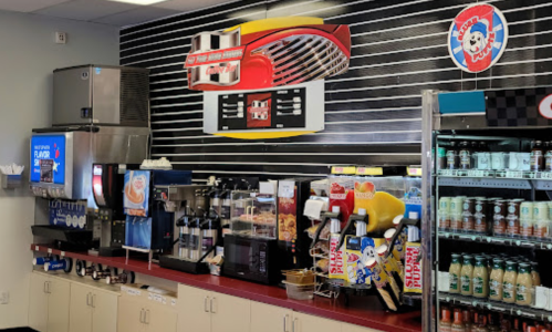 A colorful fast-food drink station with soda dispensers, ice cream machines, and a display of snacks.