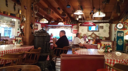 Cozy restaurant interior with checkered tablecloths, wooden decor, and patrons enjoying their meals.