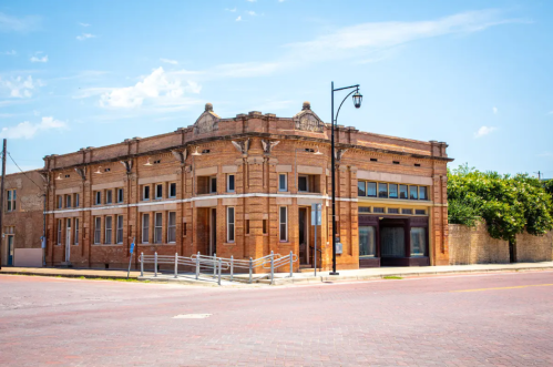 Historic brick building on a corner, featuring decorative architectural details and a clear blue sky above.