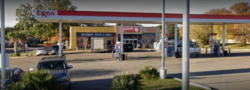 Gas station with Exxon branding, featuring a taco restaurant and a convenience store in the background.
