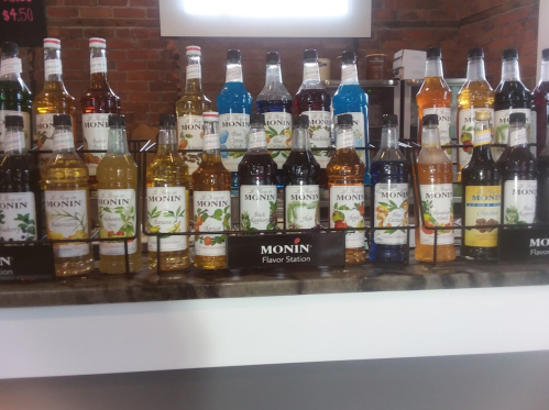A display of various Monin flavored syrups in colorful bottles arranged on a counter.