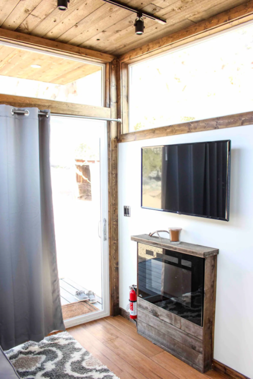 Cozy interior with wooden accents, a TV, mini fridge, and a door leading to an outdoor area.