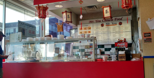 A Chinese food counter with a menu, takeout containers, and decorative lanterns in a casual dining setting.