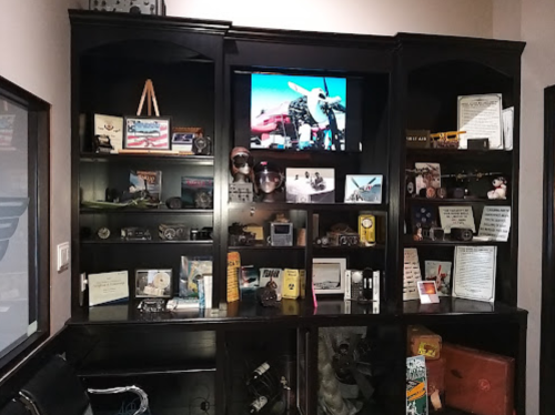 A display cabinet filled with vintage cameras, aviation memorabilia, and photographs, showcasing a collection of historical items.