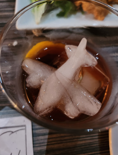 A close-up of a drink with ice shaped like an airplane, resting in a glass.