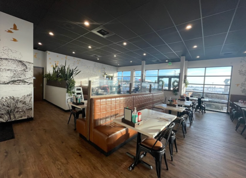 Interior of a restaurant featuring brown booths, wooden floors, and large windows with a view.