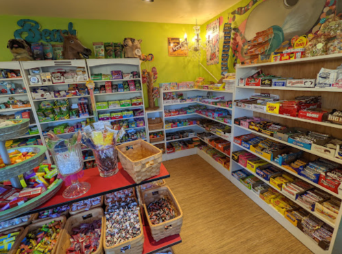 A colorful candy shop filled with various sweets, snacks, and treats displayed on shelves and tables.