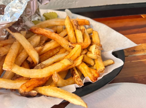 A close-up of golden, crispy French fries served on a paper-lined plate.