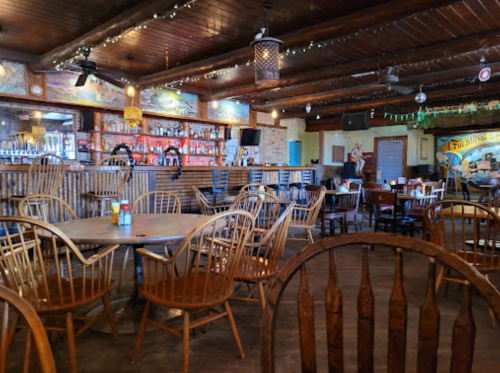 A rustic restaurant interior with wooden chairs, a bar, and colorful decor, creating a cozy atmosphere.