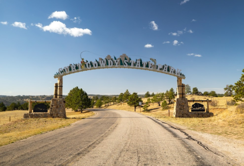 Entrance archway to Custer State Park, with a clear blue sky and rolling hills in the background.