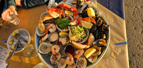 A large seafood platter featuring shrimp, oysters, crab, mussels, and lemon wedges on a table.