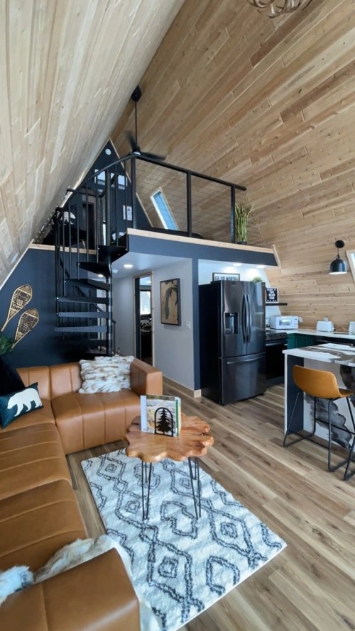 Cozy modern interior with wooden walls, a spiral staircase, leather sofa, and a stylish dining area.