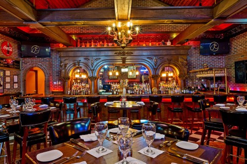Elegant restaurant interior featuring a bar, wooden tables, and warm lighting with a vintage ambiance.