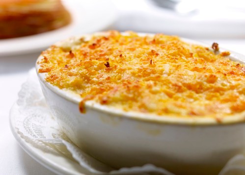 A creamy baked dish with a golden, crispy topping, served in a white dish on a lace doily.