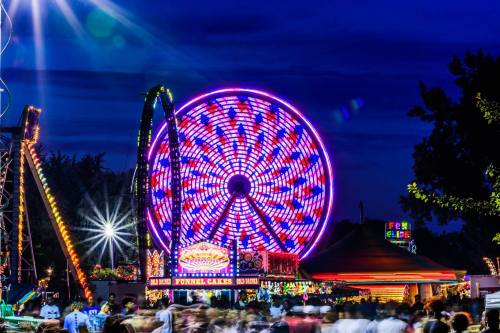 A vibrant carnival scene at night, featuring a colorful Ferris wheel and crowds enjoying the festivities.