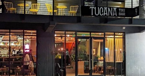 Exterior view of Tucana Tiki Bar, featuring a modern design with yellow chairs and a welcoming atmosphere.