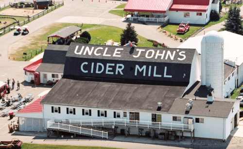 Aerial view of Uncle John's Cider Mill, featuring a large sign and surrounding buildings with red roofs.