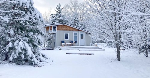 A cozy cabin surrounded by snow-covered trees in a winter landscape.