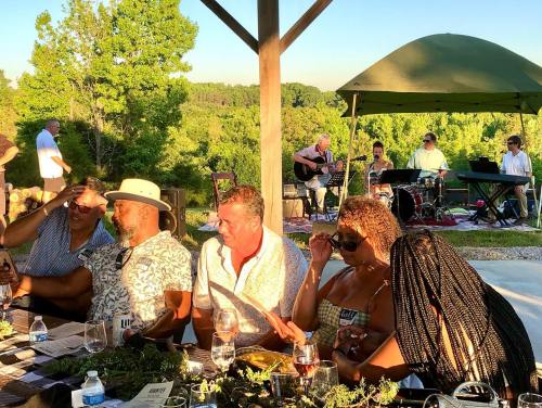A group of people enjoying a meal outdoors, with musicians performing under a tent in the background.