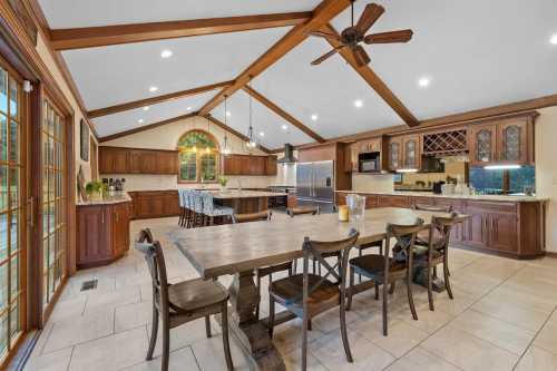 Spacious kitchen with wooden beams, large dining table, and modern appliances, featuring warm cabinetry and natural light.