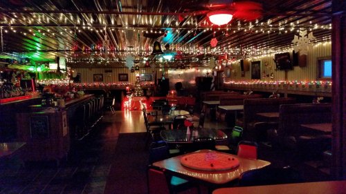 Cozy restaurant interior decorated with colorful lights, booths, and a bar, creating a warm, inviting atmosphere.