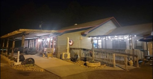 A cozy restaurant exterior at night, featuring outdoor seating and warm lights illuminating the entrance.