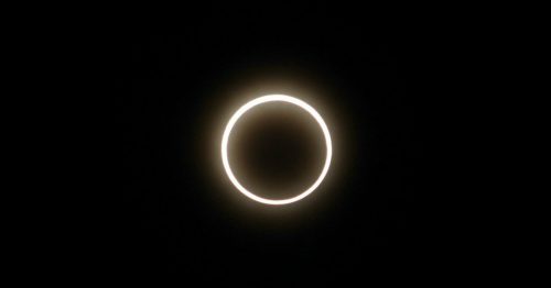 An annular solar eclipse, showing a bright ring of sunlight around the dark silhouette of the moon.