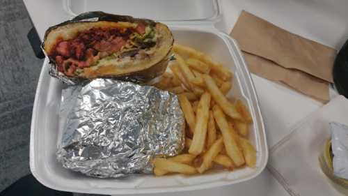 A takeout container with a half-eaten burger and a side of golden French fries.