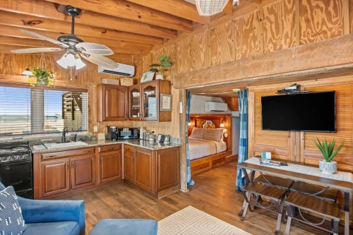 Cozy interior of a cabin featuring a kitchen area, living space, and a bedroom with wooden accents and natural light.