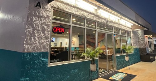 A brightly lit restaurant exterior at night, featuring large windows and an "OPEN" sign.