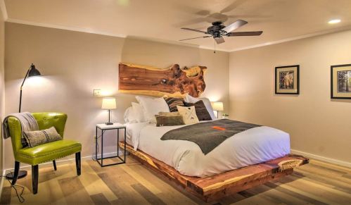 Cozy bedroom featuring a wooden bed frame, green chair, ceiling fan, and warm lighting.