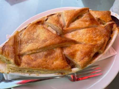 A golden-brown pastry dish, sliced into triangular pieces, served on a white plate with a fork beside it.