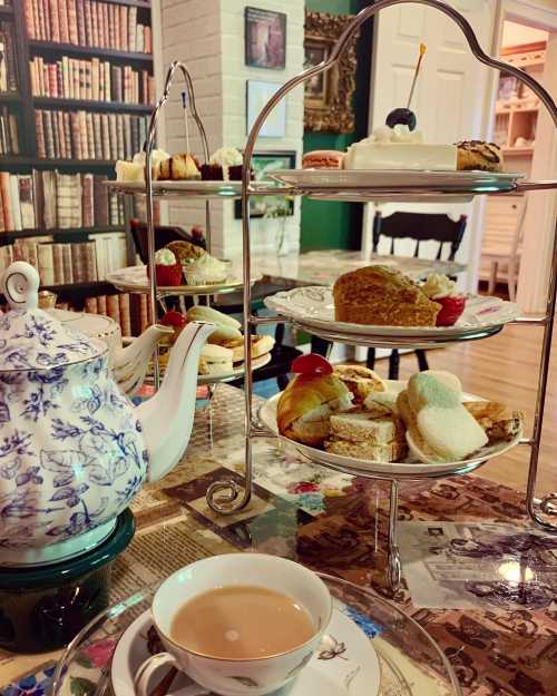 A tea set with a tiered stand of pastries and a cup of tea, surrounded by a cozy library backdrop.