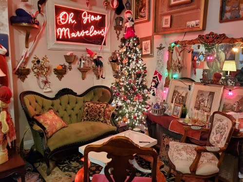 Cozy vintage room decorated for the holidays, featuring a Christmas tree, festive lights, and a neon sign.