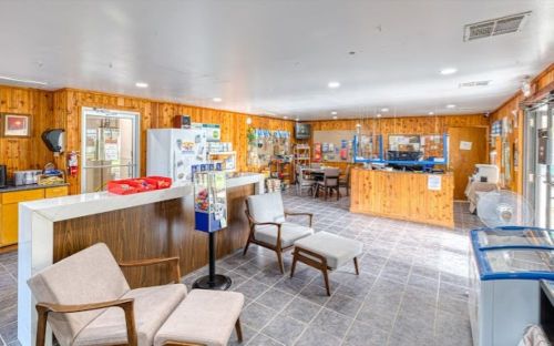 Interior of a cozy reception area with wooden walls, seating, a service counter, and various amenities.