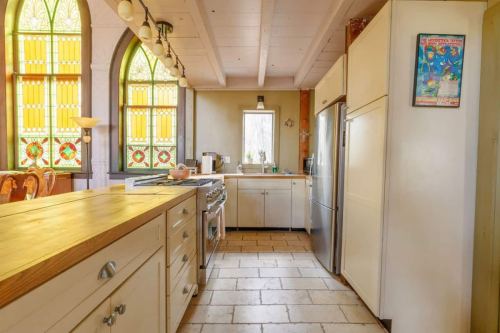 Bright kitchen with wooden countertops, stainless steel appliances, and colorful stained glass windows.