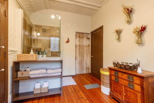 Bright bathroom with a glass shower, wooden accents, neatly arranged towels, and decorative wall vases.