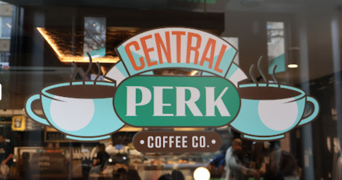 Sign for "Central Perk Coffee Co." featuring coffee cups and steam, with a cozy café atmosphere in the background.