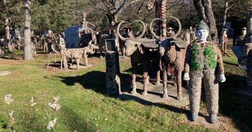 A whimsical outdoor art installation featuring sculptures of animals and human figures made from various materials.