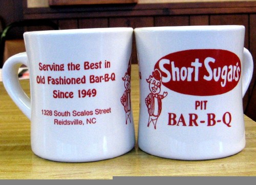 White coffee mug featuring "Short Sugars Bar-B-Q" logo and text about serving BBQ since 1949 in Reidsville, NC.