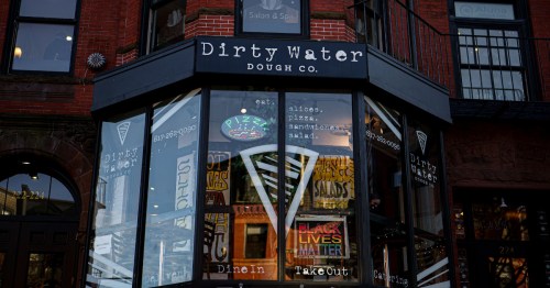 Exterior of Dirty Water Dough Co. with large windows displaying menu items and a "Black Lives Matter" sign.