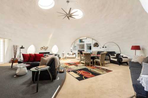 A modern, circular living space with unique architecture, featuring cozy seating, a dining area, and decorative accents.