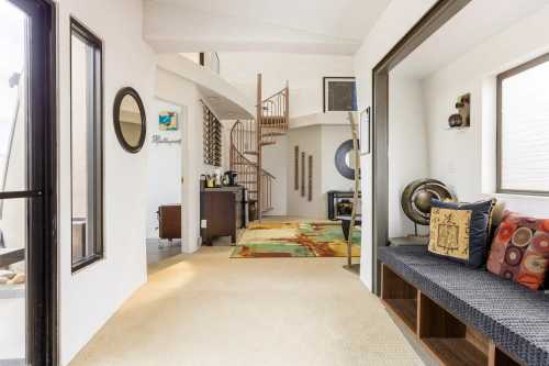 Bright, modern interior with a spiral staircase, cozy seating area, and decorative elements in a spacious layout.