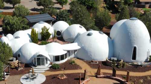 Aerial view of unique white dome-shaped structures surrounded by greenery and landscaped gardens.